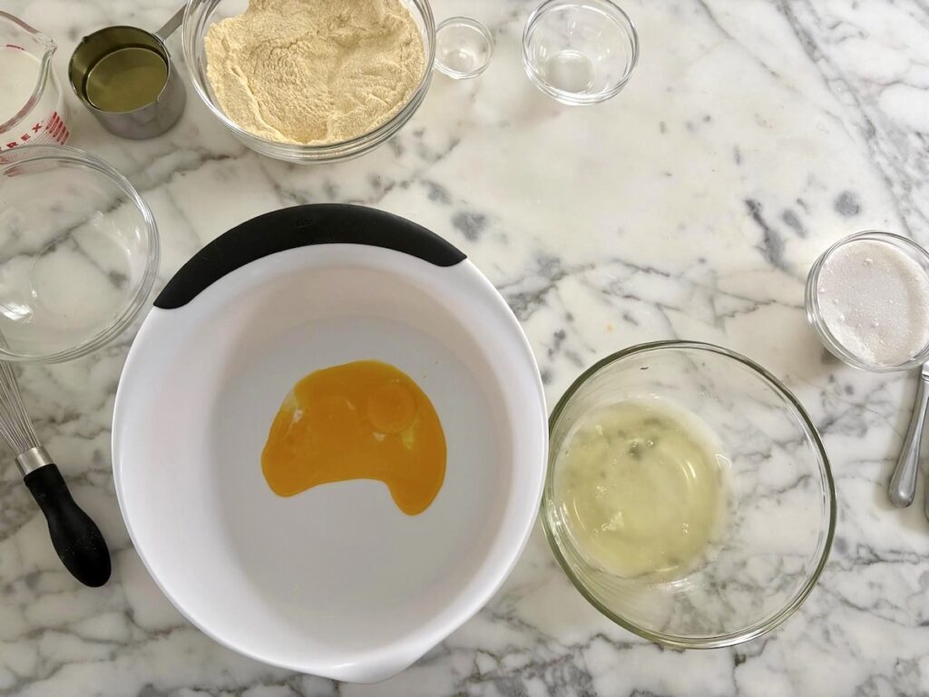Egg yokes separated into a large white mixing bowl and whites in a medium glass bowl for this Bolo de Fuba, Cornmeal Cake, recipe.