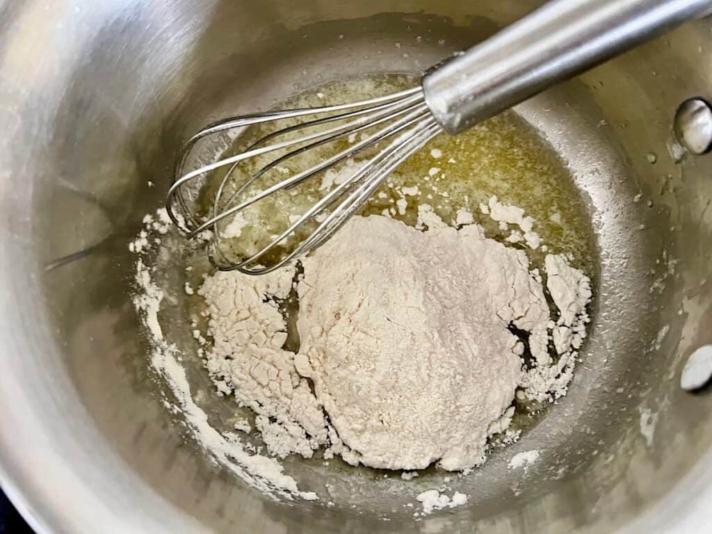 Melted butter and flour in saucepan with whisk about to be mixed for Bechamel Sauce Lasagna.