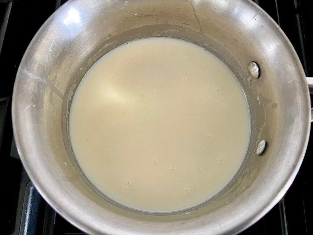 Milk whisked into the roux (butter and flour) in a saucepan for Bechamel Sauce Lasagna.