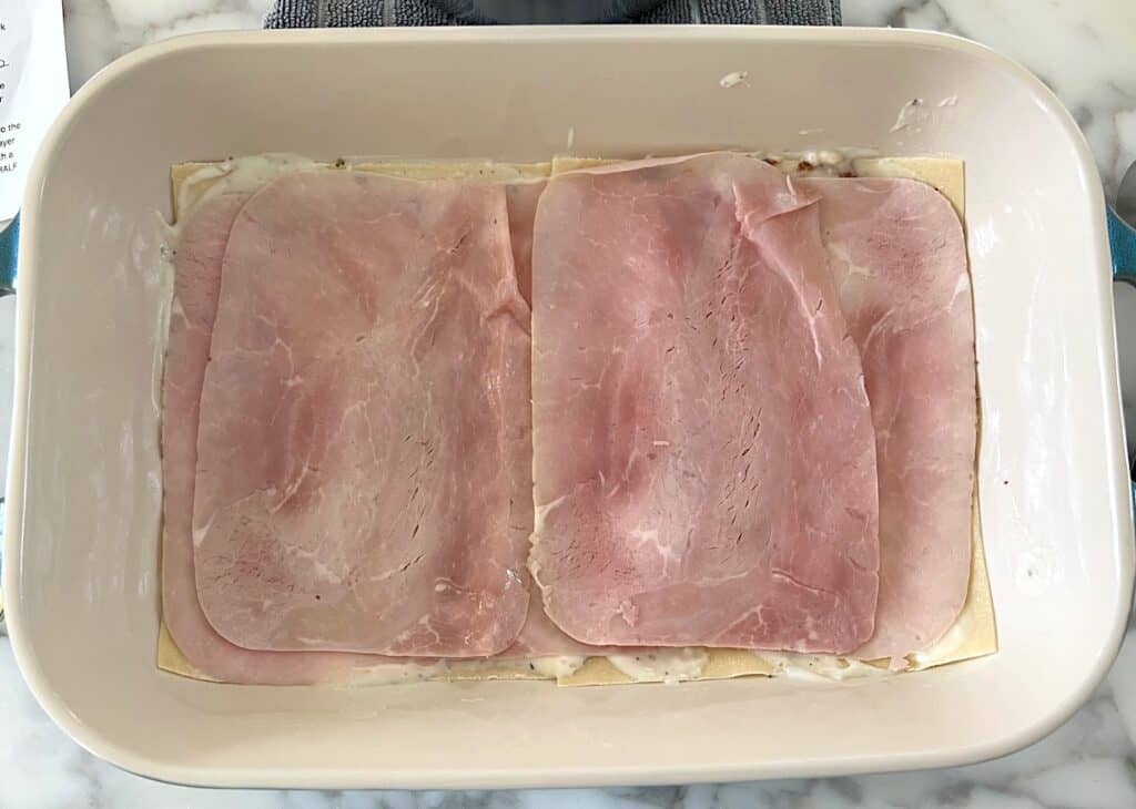 Ham slices layered on to the lasagna sheets in the casserole dish for the Bechamel Sauce Lasagna recipe.