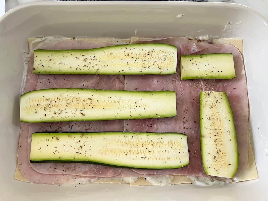 Zucchini slices layered on top of the ham slices in the casserole dish for the the Bechamel Sauce Lasagna recipe.
