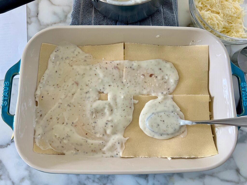 More pasta sheets and bechamel sauce being layered ono the lasagna.