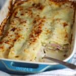 Bechamel Sauce Lasagna In a casserole dish with a piece taken out from corner and spoon in it's place.
