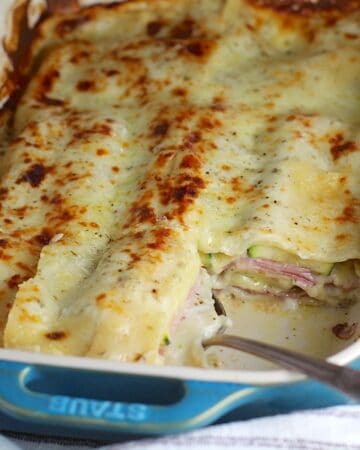 Bechamel Sauce Lasagna In a casserole dish with a piece taken out from corner and spoon in it's place.