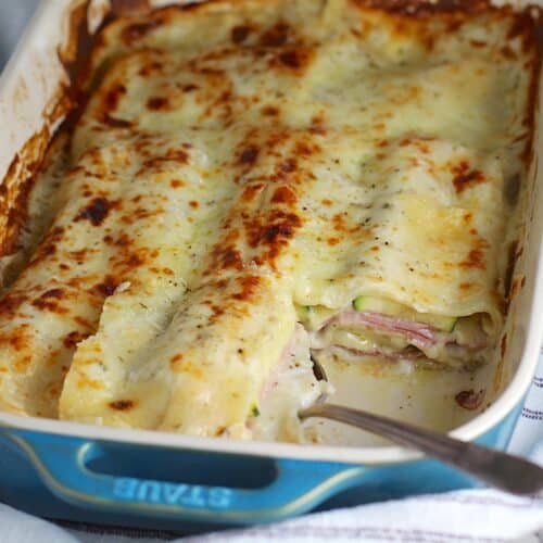 Bechamel Sauce Lasagna In a casserole dish with a piece taken out from corner and spoon in it's place.